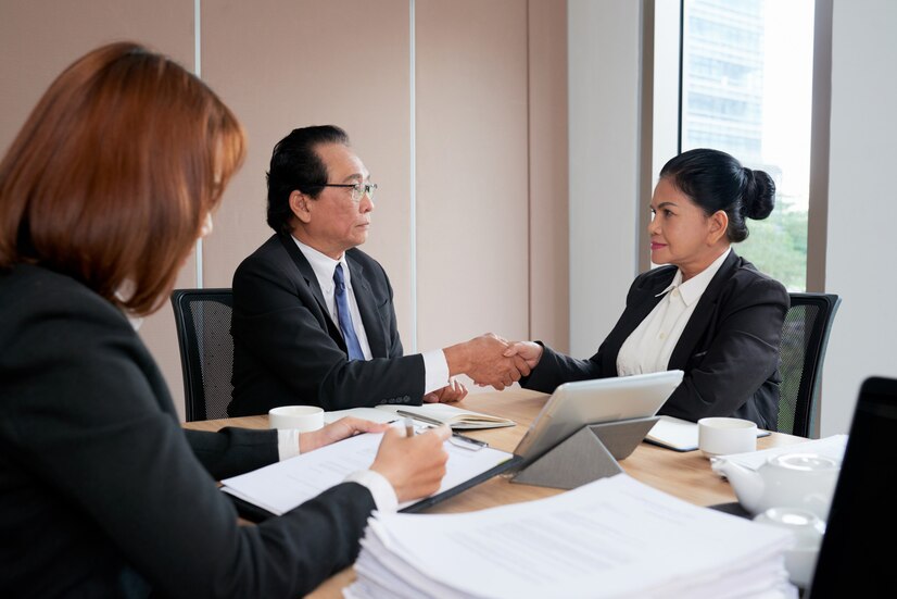 two-business-executives-handshaking-close-deal-while-secretary-protocoling-minutes-meeting_1098-18562